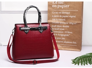 Detail view of red crocodile pattern handbag featuring black and white snake print handles