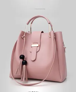 Detail of dusty pink handbag with gold metal handles and beaded tassel accents