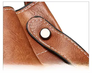Detailed macro view of brown leather bucket bag featuring white stitching and metal rivet