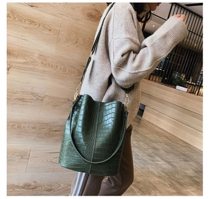 Detail view of the green crocodile texture bucket bag with adjustable straps and gold hardware