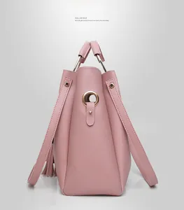 Detail of pink pebbled leather tote bag featuring metal ring handles and stylish tassels