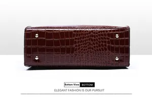Detail view of burgundy croc-embossed tote bag bottom with four gold protective metal feet