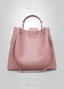 Detail of light pink crossbody bucket bag with golden ring handle and smooth leather texture