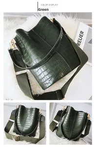 Detail view of dark green crocodile texture bucket bag with wide olive strap