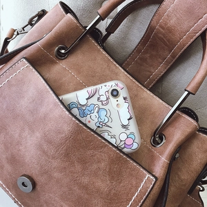 Brown vintage leather bucket bag with white contrast stitching and wide shoulder strap