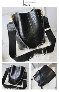 Detail view of black crocodile pattern bucket bag with wide woven strap and gold hardware