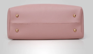 Detail view of pink leather bag bottom with four protective gold metal studs and stitching