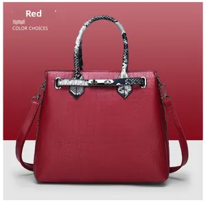 Detail of red embossed leather handbag with faux snakeskin handle and metallic turn-lock