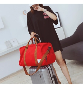 Sac de voyage rouge sur valise montrant la fonction de fixation et poche à chaussures