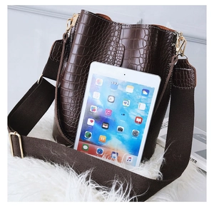 Detail view of brown crocodile texture bucket bag with wide strap and tablet for size reference