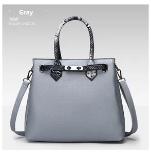 Close-up of the gray croc-patterned handbag featuring snake-print handles and metal lock