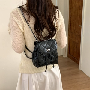 Women's black quilted mini backpack with metal chain straps and silver lock closure