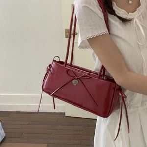 Minimalist deep red underarm bag in glossy finish with bow and heart pendant detail