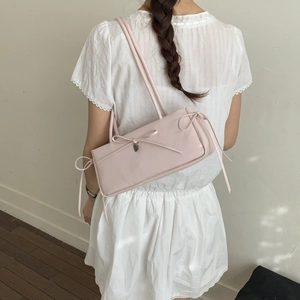 Pink rectangular underarm bag with bow details and silver heart charm on model