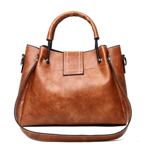 Retro brown bucket tote bag with metal handles and white stitching on white background