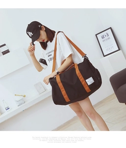 Vista dettagliata della borsa da viaggio nera con manici arancioni a contrasto vivace