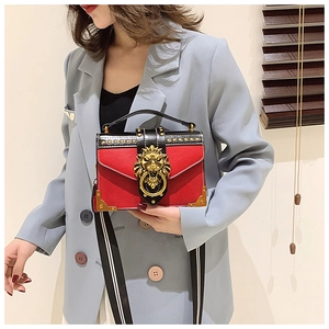 Detail of red and black retro bag featuring a gold lion head clasp and metal rivets