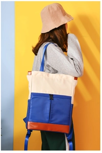Rear view of model wearing a tri-color waterproof nylon backpack with leather base detail