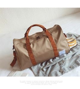 Dettaglio borsone da viaggio in tela con manici arancioni, tasca scarpe e tag Happy Travel
