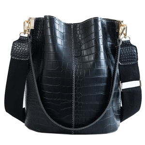 Black crocodile pattern bucket bag with white stitching and wide crossbody strap