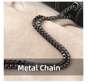 Detail of gunmetal box chain and metallic rivets on black leather crossbody bag