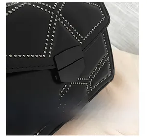 Close-up of black leather bag featuring silver metal studs and matte geometric lock