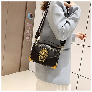 Detail of black leather crossbody bag with golden lion head emblem and metal studs