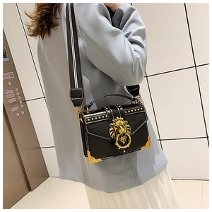 Detail of black pebbled leather crossbody bag with golden lion head buckle and metal corners