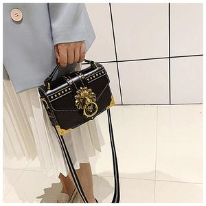 Close-up of black leather crossbody bag with golden lion head buckle and metal rivets