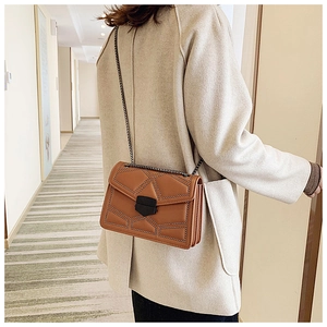 Close-up of caramel crossbody bag with geometric quilting and rivet details