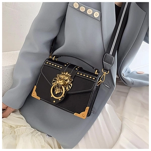 Close-up of black leather bag with golden lion head buckle and rivet detailing