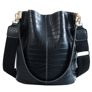 Black crocodile embossed leather bucket bag with white stitching and wide fabric strap