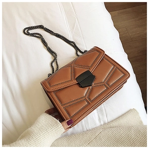 Macro shot of dark brown faux leather bag with bronze studs and metal chain strap