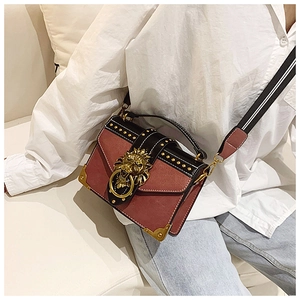 Detail of red and black leather crossbody bag with lion head buckle and metal studs
