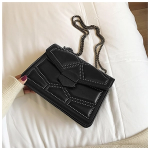 Close-up of black leather chain bag with geometric stitching and dark metal studs
