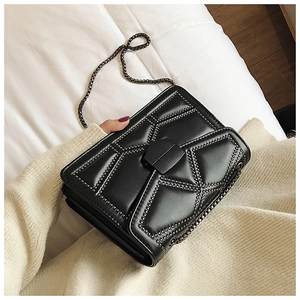 Close-up of black geometric quilted bag featuring metallic studs and metal chain strap