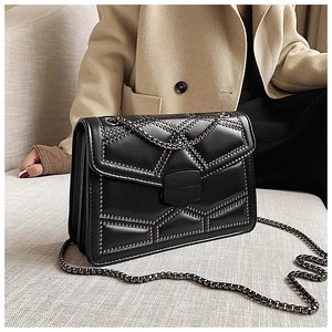 Detailed close-up of a black crossbody bag with metal rivets and a stylish chain strap