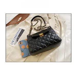 Detail view of black quilted faux leather crossbody bag with gold chain and metal lock