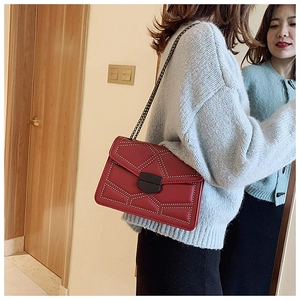 Detail of burgundy crossbody bag with silver studs and quilted geometric lines