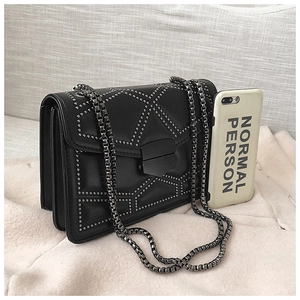 Close-up of black crossbody bag with silver rivet patterns and chunky metal chain