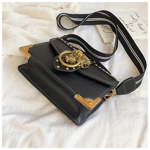 Close-up of black lychee grain bag with gold lion head hardware and striped strap