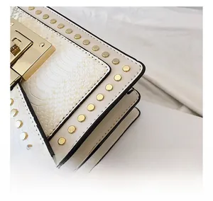 Detail of cream leather handbag with snake pattern flap and golden rivet studs