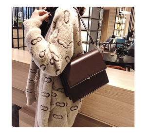 Détail d'un sac bandoulière marron foncé motif pierre porté avec un cardigan