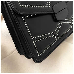 Detail view of black leather crossbody bag with silver rivet studs and accordion folds