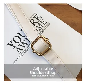 Detail view of white leather shoulder strap with golden metal adjustment buckle