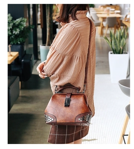 Close-up of vintage brown doctor bag featuring hex rivets and metallic clasp detail