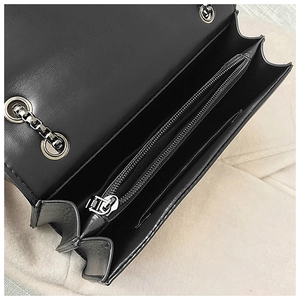 Interior detail of black leather chain bag showing three compartments and silver hardware