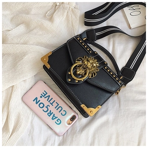 Detail of vintage PU leather crossbody bag with golden lion head buckle and rivets