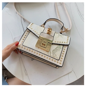 Detail of white snake-textured handbag with gold studs, square lock and chain strap