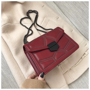 Detail of dark red rivet bag with silver studs and chain strap on wool coat